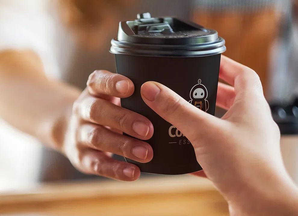 A hand holding a CoffeeBot cup