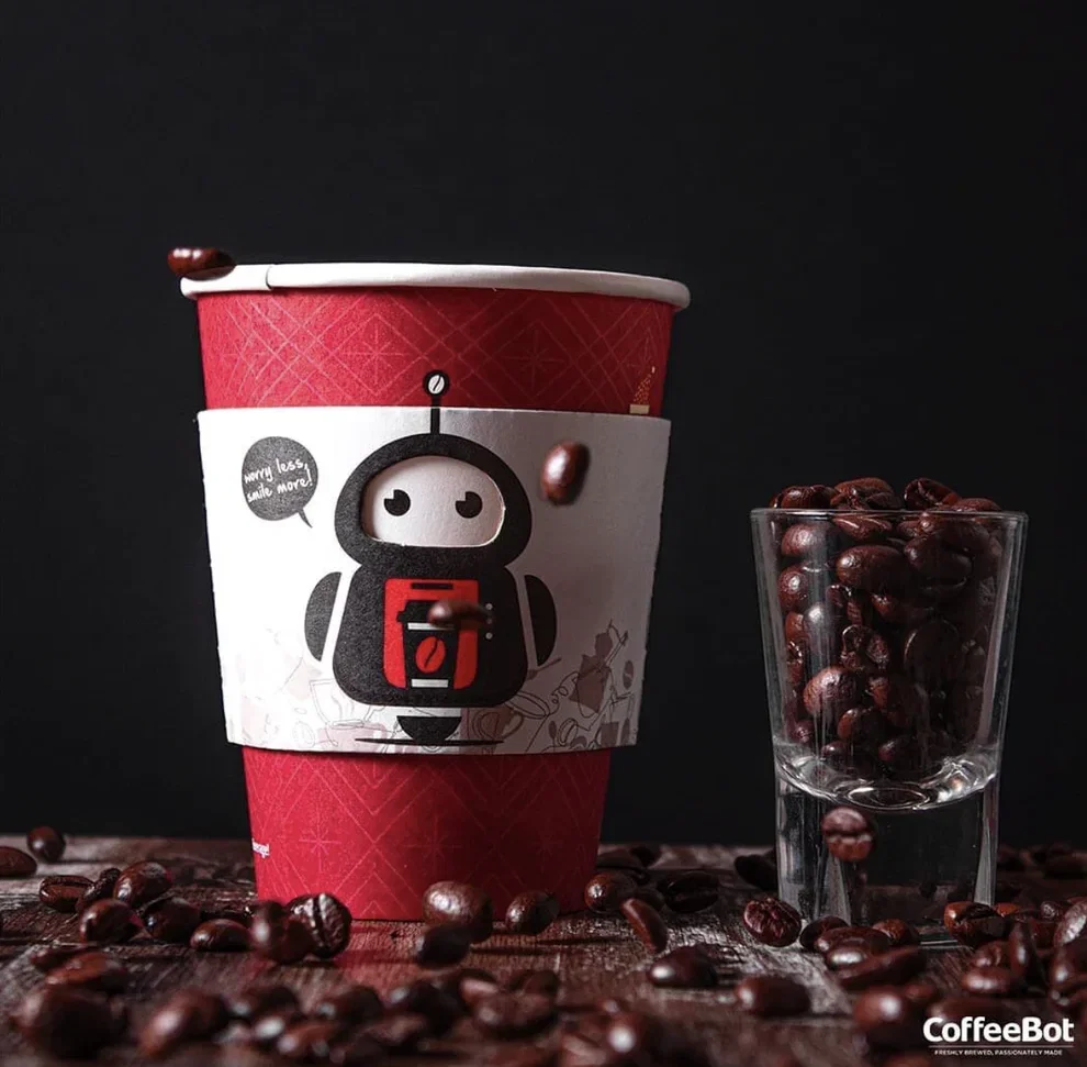 CoffeeBot cup beside a glass of roasted beans