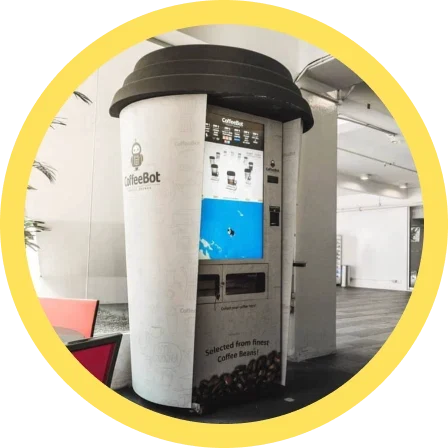 A CoffeeBot machine built to look like a giant takeaway cup, standing in a lobby.