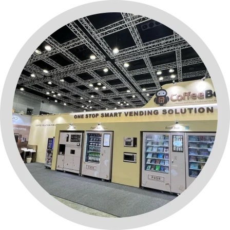 A CoffeeBot exhibition stand lined with smart vending machines under a One Stop Smart Vending Solution banner.